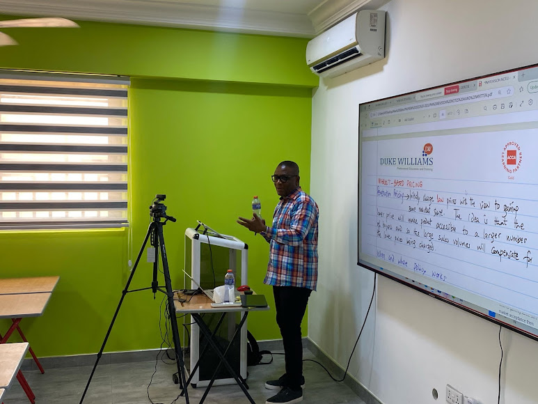 Tutor presenting beside an interactive screen in a classroom